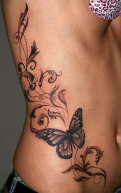 a woman's stomach with a butterfly tattoo on the side and an intricate design