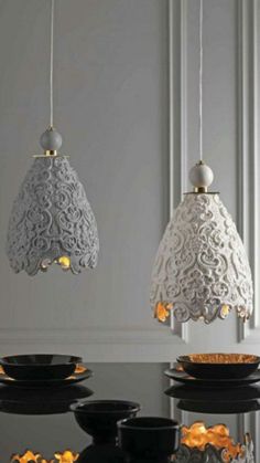 three white and black lights hanging from the ceiling above a dining room table with gold accents