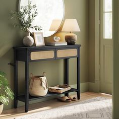 a black console table with a mirror on top and some plants in front of it