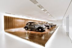 there are many old cars on display in the room with wood paneling and white walls