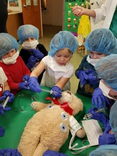 a group of children wearing surgical garb around a teddy bear