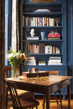 a dining room table with chairs and bookshelf in the background