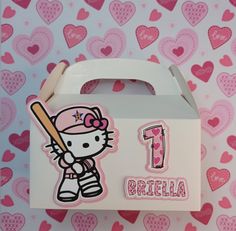 a hello kitty birthday card in a white box with pink hearts on the wall behind it