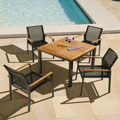 an outdoor table and chairs next to a swimming pool