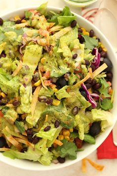 a salad with black beans, lettuce and avocado in a white bowl