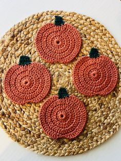 three crocheted pumpkins sitting on top of a woven placemat