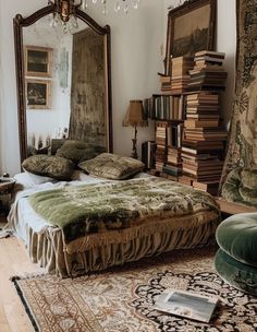 a large bed sitting next to a tall mirror in a room with lots of books on it