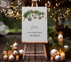 an easel with candles and christmas decorations around it on a wooden table in front of lights