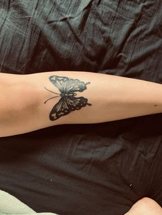 a woman laying on top of a bed with a butterfly tattoo on her arm and leg