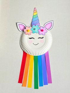 a paper plate with a unicorn face on it and rainbow sticks sticking out of it