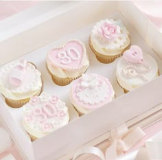 cupcakes decorated with pink and white icing in a box