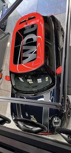 an overhead view of a red and black car with its hood up in a showroom