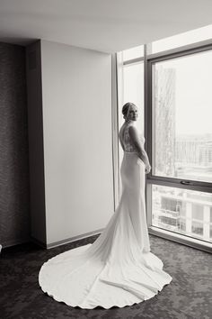 a woman in a wedding dress looking out the window