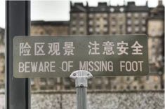 there is a sign that says beware of missing foot on the street pole in front of some buildings