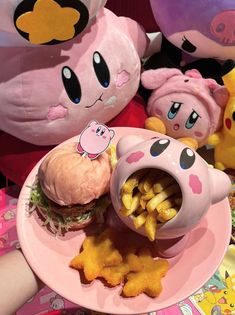 a pink plate topped with a sandwich and fries next to stuffed animals on the table