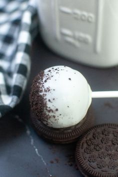 two oreo cookies on a stick next to a jar of milk