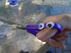 someone is holding scissors with googly eyes on them