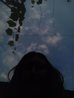 a woman's face is shown in front of the sky with leaves on it