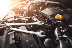 the engine compartment of a car with wrenches and other tools on it's hood