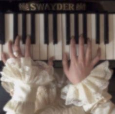 someone is holding their hands on the keys of an organ keyboard while wearing a white dress