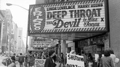 black and white photograph of people holding signs on the sidewalk in front of a theater