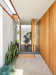 an entry way leading to a house with wood paneling and plants on either side