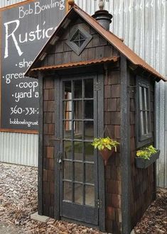 a small wooden building sitting in front of a metal wall with a sign on it