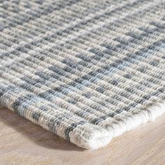 a close up of a rug on a wooden floor with white and blue stripes in the middle