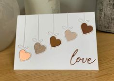 a card with hearts hanging from strings that says love on the front and back side