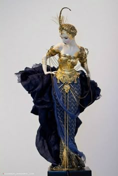 a statue of a woman dressed in blue and gold, with her hands on her hips