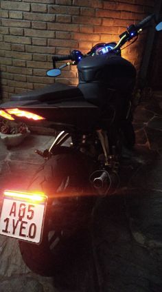 a motorcycle parked in front of a brick wall with the license plate light on it