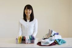 a woman standing next to a pile of clothes on top of a white countertop