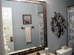 a bathroom with blue walls and a white toilet in the corner next to a large mirror