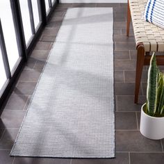 a white rug on the floor next to a chair and a cactus in a pot