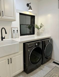 a washer and dryer in a small room with white cabinets on the wall