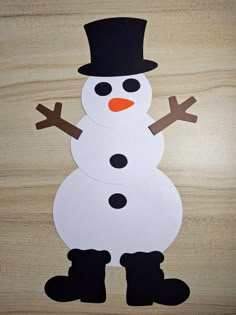 two snowmen made out of paper sitting on top of a wooden table