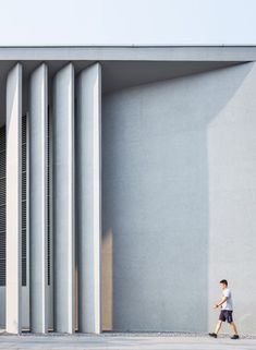 a man walking past a tall white building