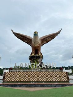 a large bird statue sitting on top of a lush green field