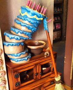 there is a large cake on top of a wooden cabinet with a broom sticking out of it