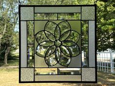 a stained glass window with a flower on it in the middle of some grass and trees