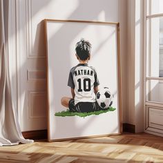 a boy sitting on the ground with a soccer ball in front of him