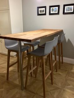 a wooden table with four grey chairs in front of it and pictures on the wall