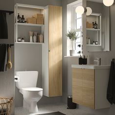 a white toilet sitting in a bathroom next to a sink under a mirror and lights