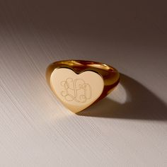 The Isabel Heart Signet Ring is the ultimate way to show off your unique style. With custom engraving options, you can make this gold ring truly one-of-a-kind. The heart and signet features add a touch of charm to any outfit. Make a statement with this playful piece! Available in 14k gold plated brass Size: 1/2" Band Width: 2mm Protected with an anti-tarnish barrier With engraving this item is FINAL SALE SKU: BYR1141 Repurposing Jewelry, Heart Signet Ring, Engraved Signet Ring, Initial Rings, Custom Signet Ring, Gold Pinky Ring, Tennis Jewelry, Signet Rings Women, Modern Jewellery Design