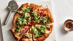 a pizza sitting on top of a white cutting board next to a bowl and spoon