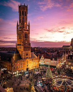 an aerial view of a christmas market in the middle of town at dusk with lights on