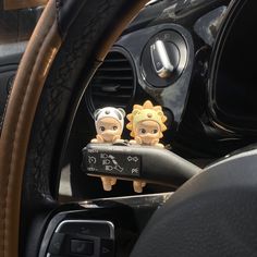 two small figurines sitting on the dashboard of a car