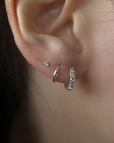 a close up of a person's ear with two small diamond earrings on it