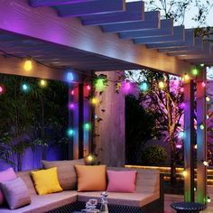 an outdoor living room with colorful lights on the ceiling and couches in the middle