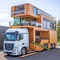 a large truck is parked in front of a building with balconies on top